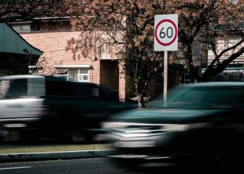 Cars driving past speed limit sign