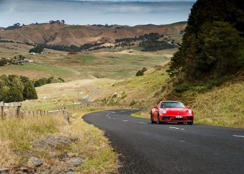 red Porsche 911 GTS driving through hills