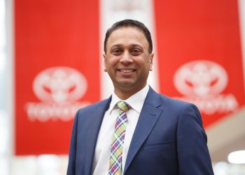 Neeraj Lala, Toyota New Zealand CEO standing in front of Toyota flags
