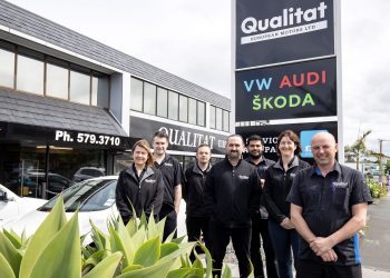 Qualitat team members standing in front of sign