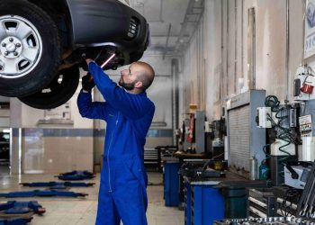 Man inspecting underside of car