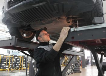 Worker inspecting underneath a car