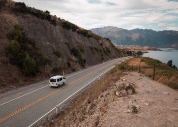 Van driving on road by lake