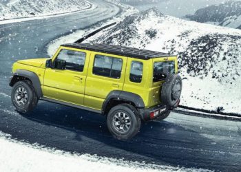 Five-door Suzuki Jimny driving around snowy corner