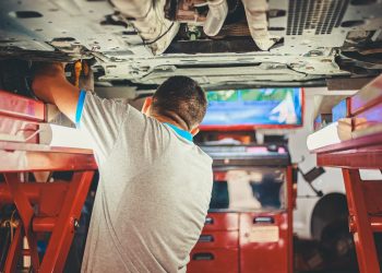 Man inspecting underside of car