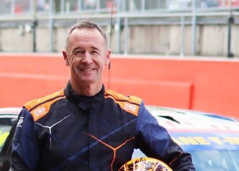 Greg Murphy standing with helmet in arms