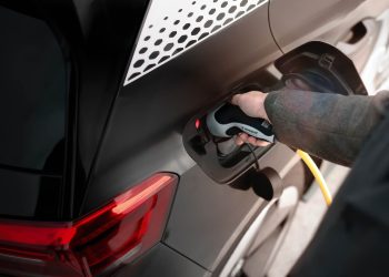 Man holding electric vehicle charging plug in car