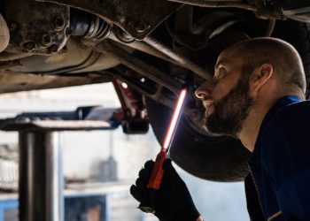 Mechanic inspecting underside of car