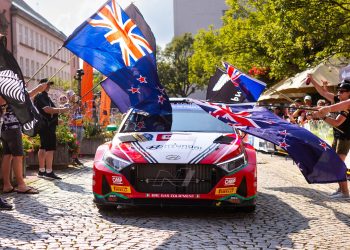 Hayden Paddon driving Hyundai i20 rally car through New Zealand flags