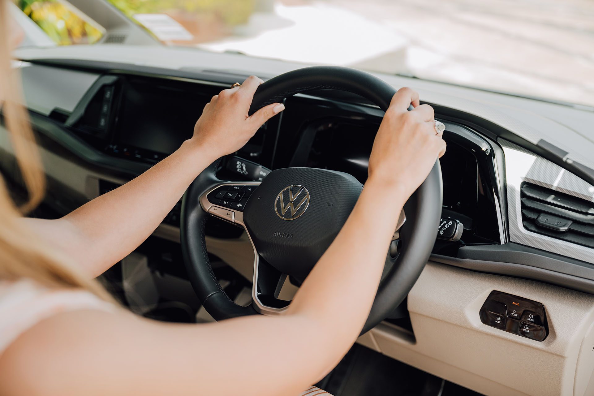 Woman holds the wheel of the VW Multivan 7 TDI incorrectly.