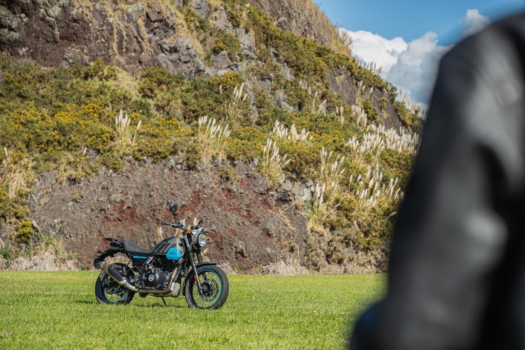 Royal Enfield Scram 411 parked on grass, in front of a mountain