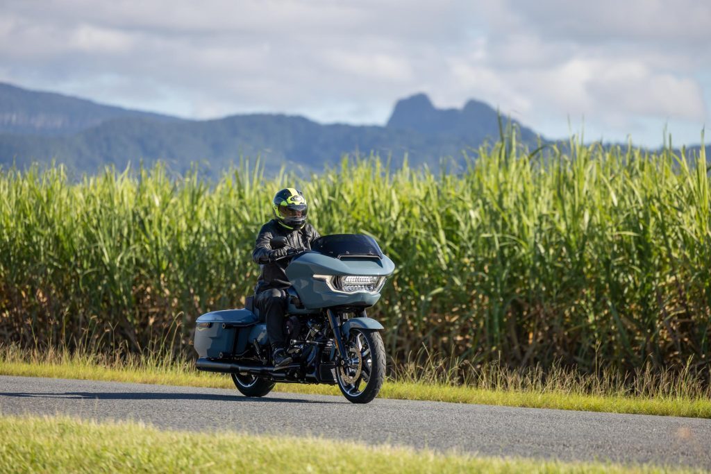 Harley-Davidson Road Glide riding along a road, with a farm behind it