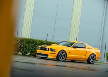 Ford Mustang GT 2007 in yellow, parked on a wet road
