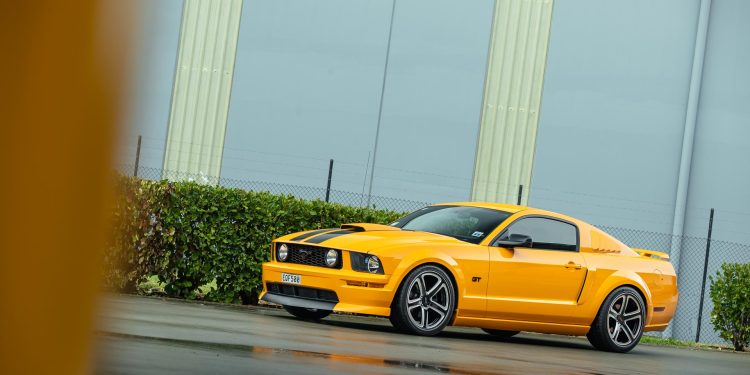 Ford Mustang GT 2007 in yellow, parked on a wet road