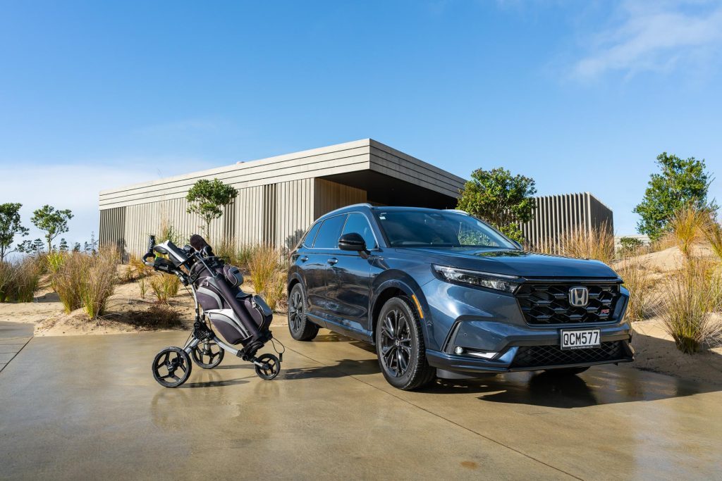 Honda CR-V RS with a golf bag next to it, near a bach