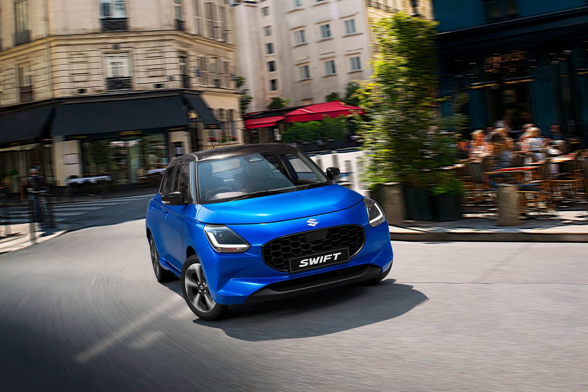 Blue fourth-gen Swift cornering in town.