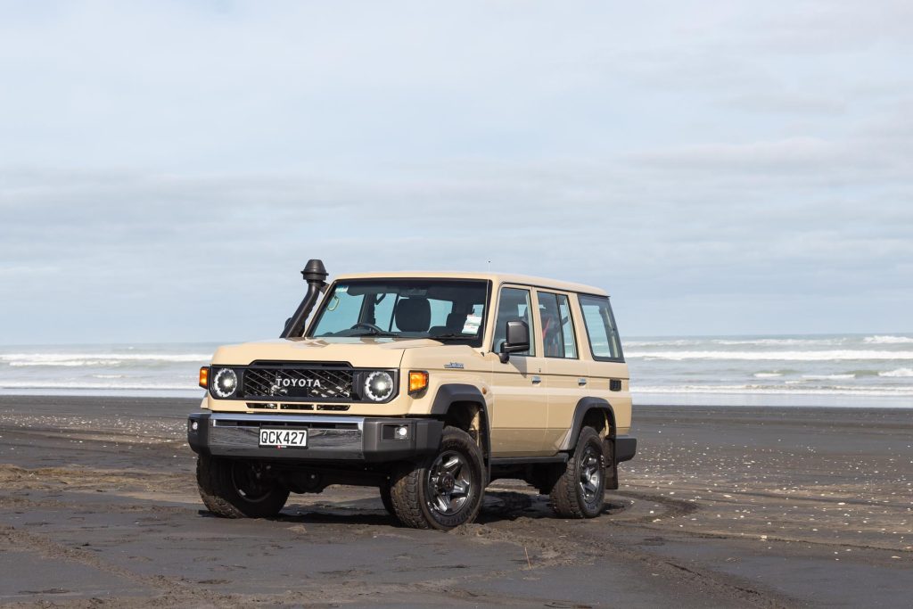 2024 Toyota Land Cruiser 70 LX Wagon parked on a Kiwi beach