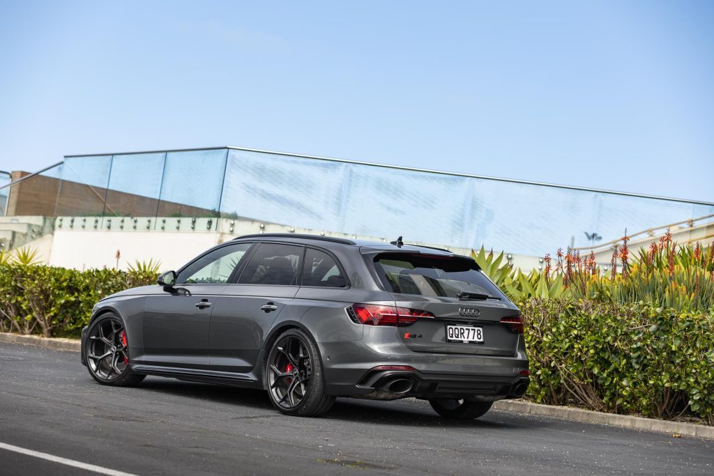 Audi RS 4 Competition Plus parked showing the rear quarter, with hedge and glass behind