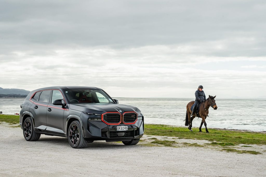 Front quarter, with a horse next to the BMW XM Label Red Edition