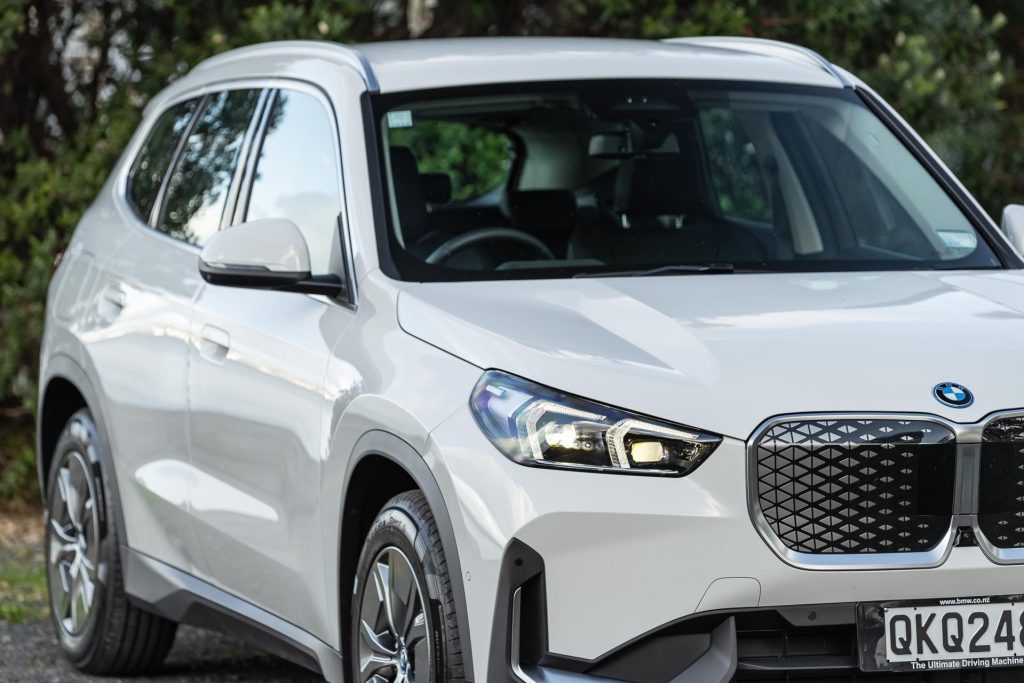 Detail shot of the 2024 BMW iX1 eDrive20's headlights, grille, and side of the car