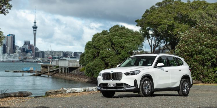 BMW iX1 in white, parked with Auckland's city skyline behind