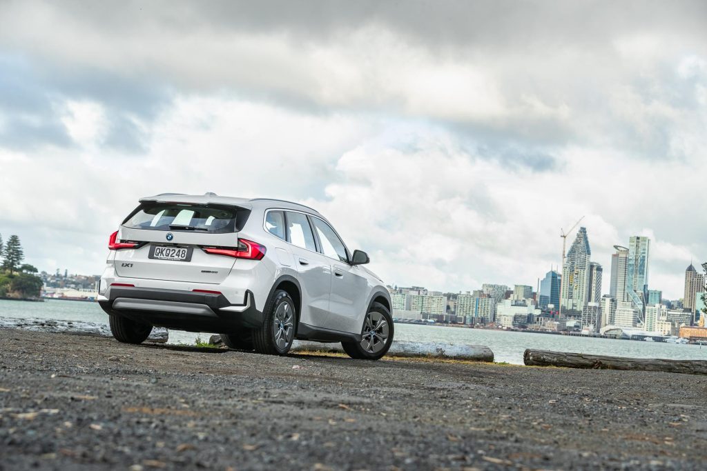 2024 BMW iX1 eDrive20 rear quarter view, showing City skyline in background