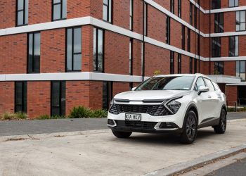 Kia Sportage front quarter angle, parked in front of a massive brick building