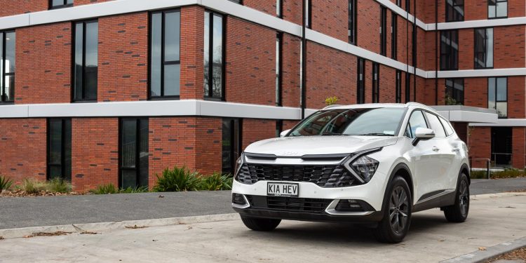 Kia Sportage front quarter angle, parked in front of a massive brick building