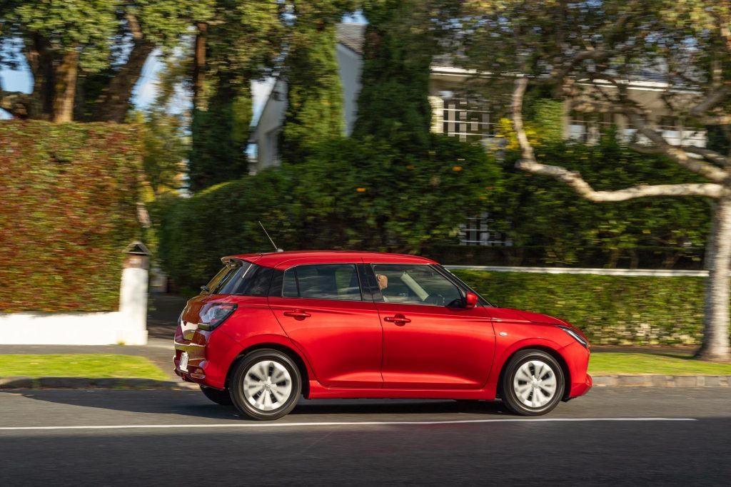 Suzuki Swift GLS in red panning shot, in upmarket area