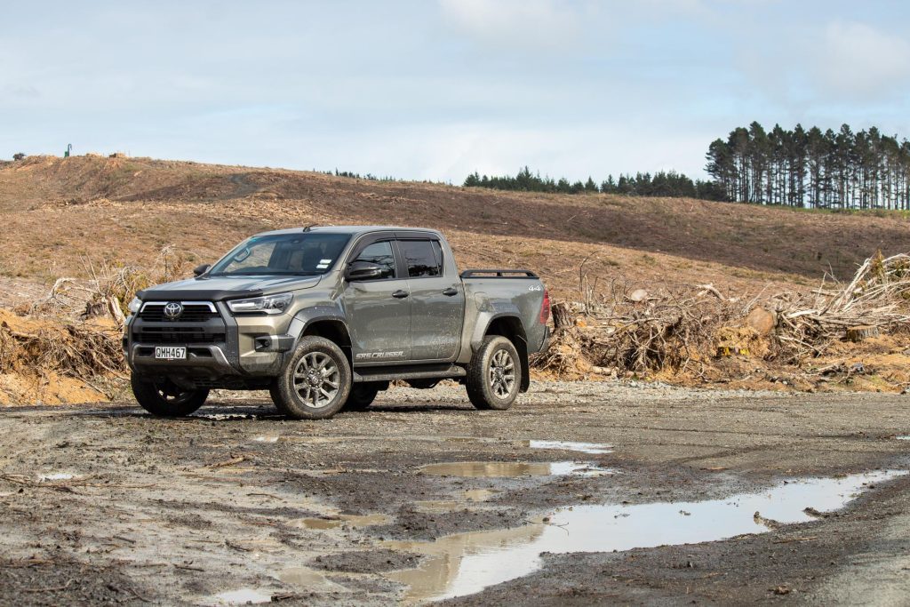 Toyota Hilux SR5 Cruiser Hybrid in grey, parked with a forestry area in behind