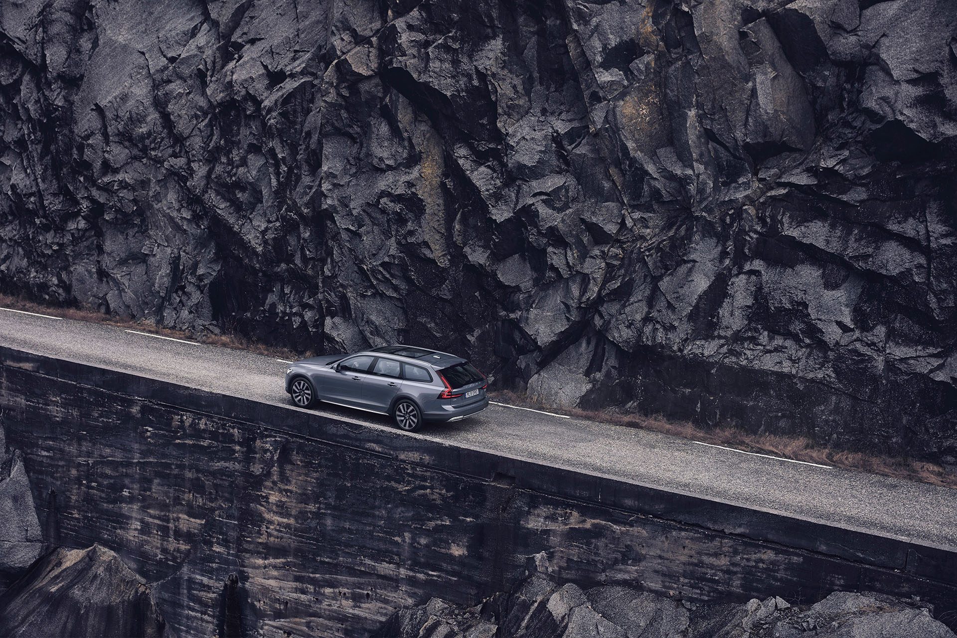 Station wagon on narrow path alongside rockface (could be Brynderwyns).