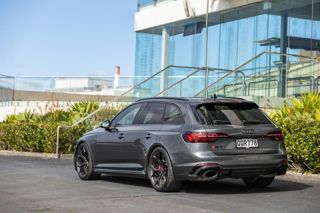 Rear quarter angle, of the RS 4 2024, in front of glass building