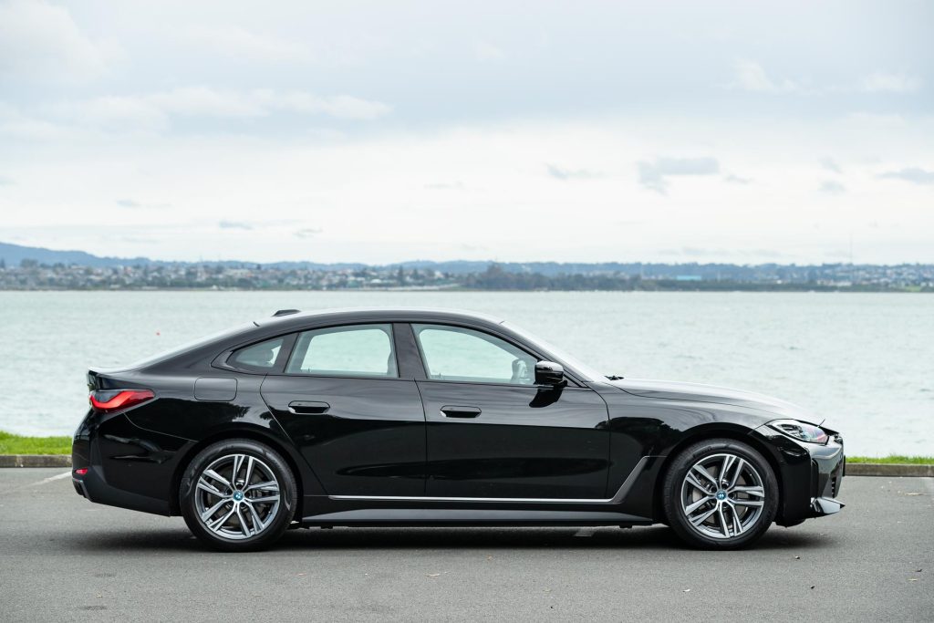 side profile of the 2024 BMW i4 eDrive35, parked in front of the water