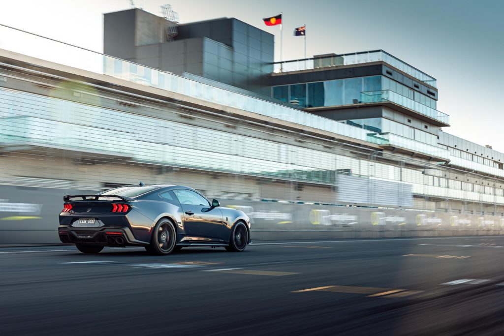 Ford Mustang Dark Horse  in black, in a rolling shot taken on a racetrack