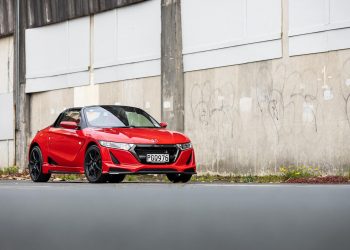 Honda S660 Mugen in red, parked in front of an urban wall