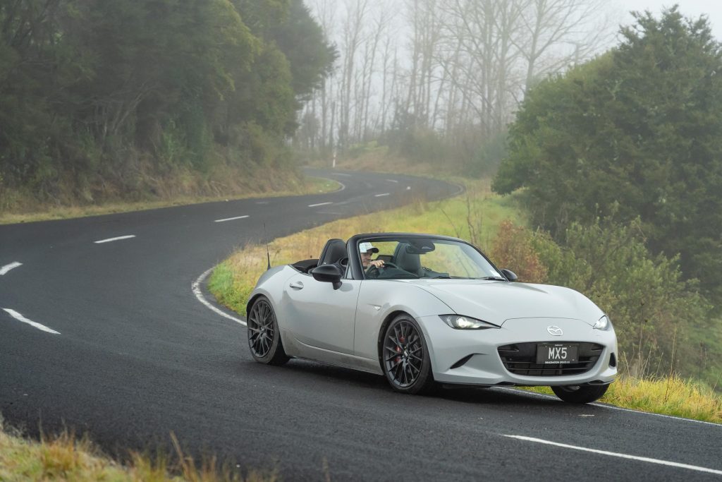 2024 Mazda MX-5 GT cornering on an S bend, with the bend shown behind the car