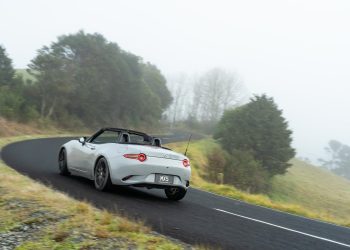 Mazda MX-5 cornering at pace, shown from the rear, on a foggy road