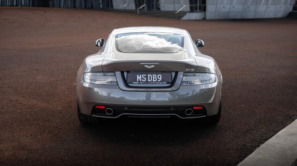 Aston Martin DB9 in silver, parked on red concrete