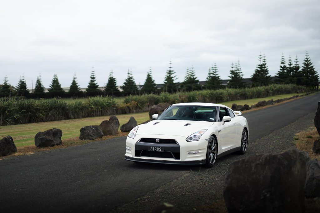 Nissan GT-R R35  in white, parked on a quiet road near rocks