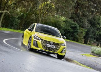 Peugeot 208 GT Hybrid in yellow, taking a corner in the wet