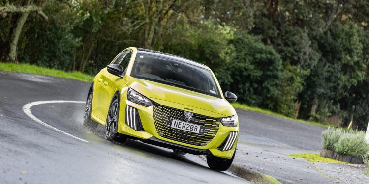 Peugeot 208 GT Hybrid in yellow, taking a corner in the wet