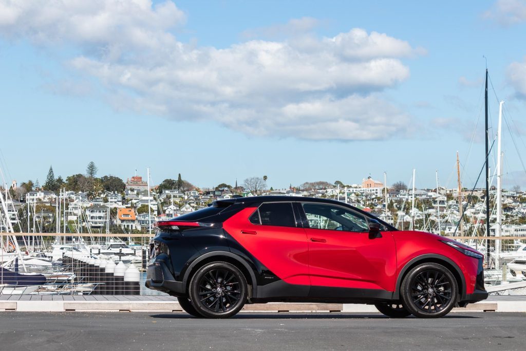 Toyota C-HR GR Sport Hybrid E-Four in red and black, next to a marina