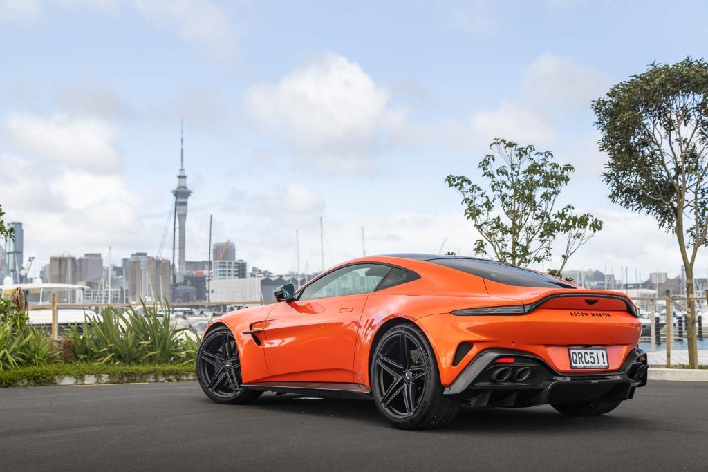 Rear quarter view, car in orange with Auckland sky tower behind