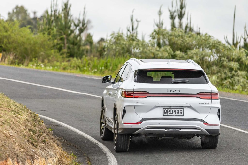 Build Your Dreams car in white, shown from the rear taking a corner