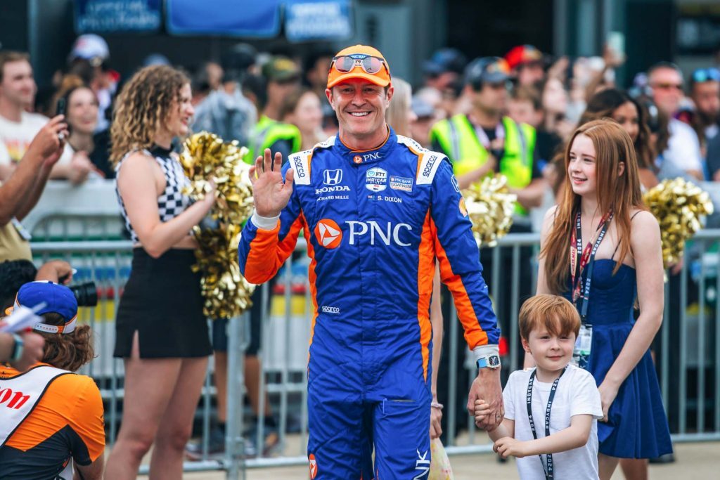 Scott waving to fans while family follows behind him