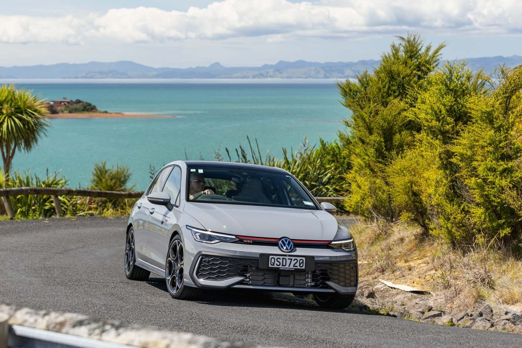 VW Golf GTI cornering with the sea behind it