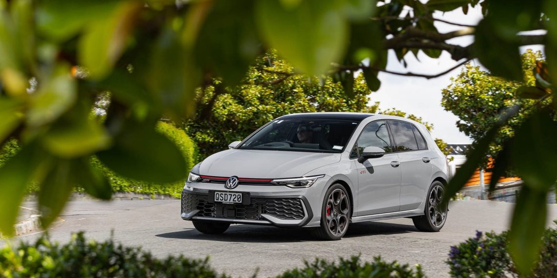 Volkswagen Golf GTI 2024 shot through trees, driving through a neighbourhood