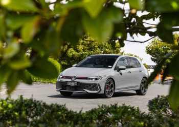 Volkswagen Golf GTI 2024 shot through trees, driving through a neighbourhood