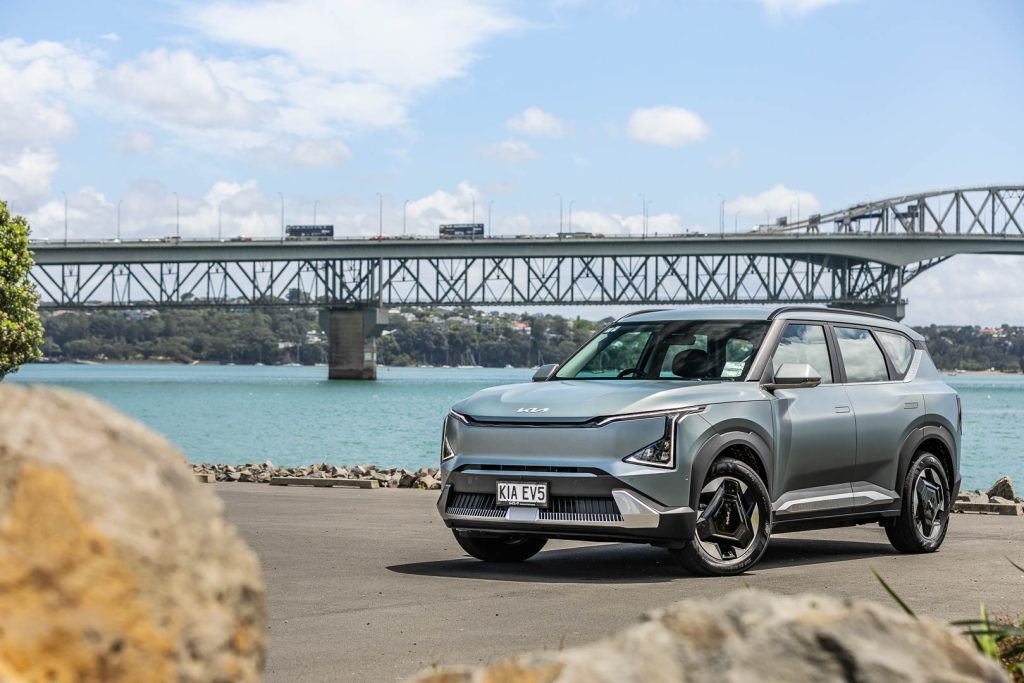 Wide front quarter shot, with harsh sunlight shining down. In front of Auckland harbour bridge