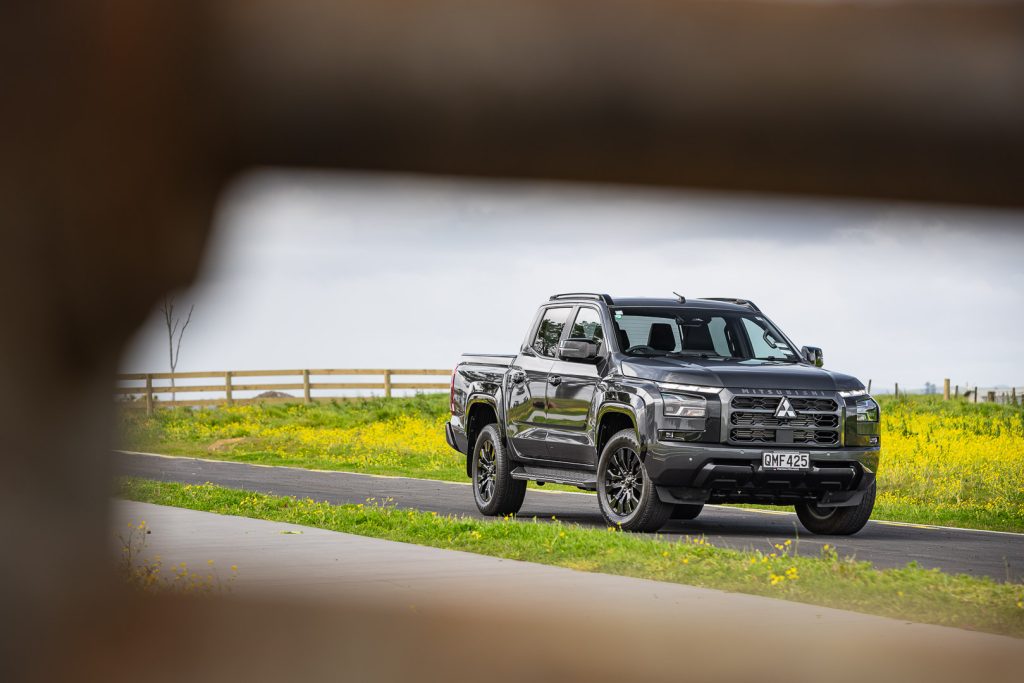 Mitsubishi Triton VRX 4x4 in black, parked next to a wildflower patch